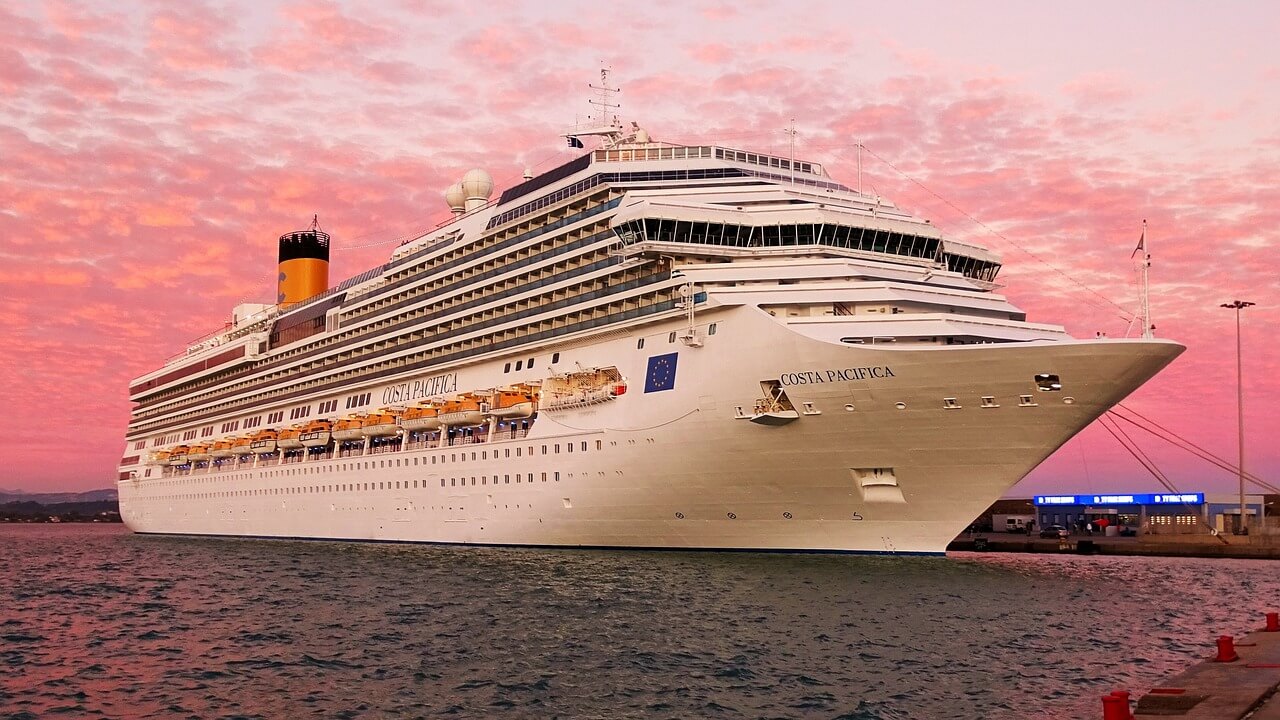 A cruise ship alongside the quay under a pink sunset sky