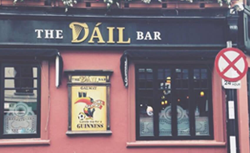 The Dail Bar in Galway, a pink painted pub front with a Guinness sign in the window