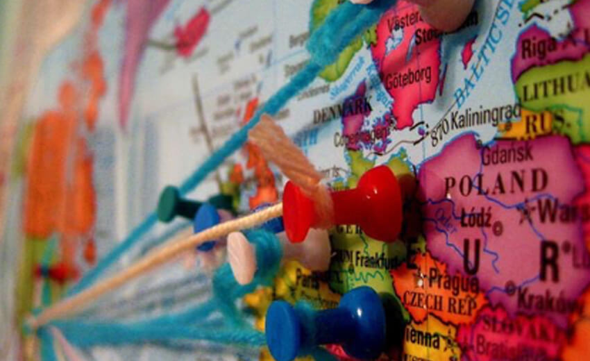 Pins and small flags stuck into a colourful wall map of Europe
