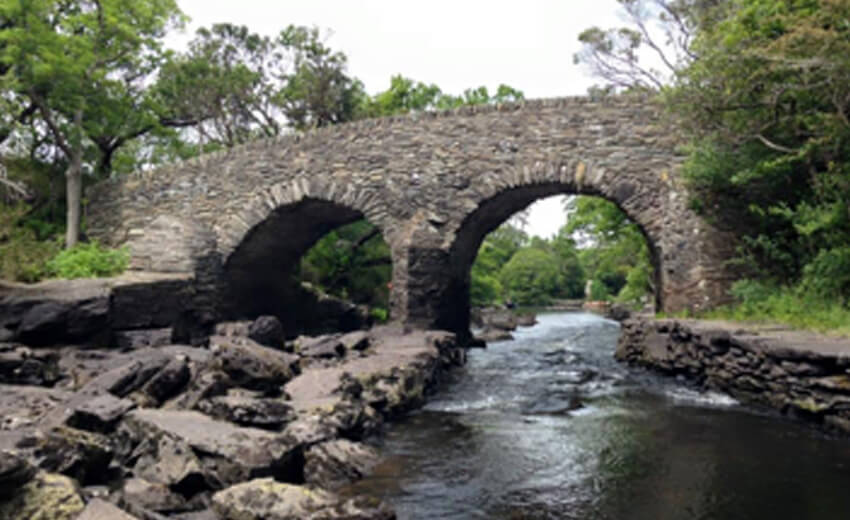 An old stone arch bridge over a river in the Gap of Dunloe