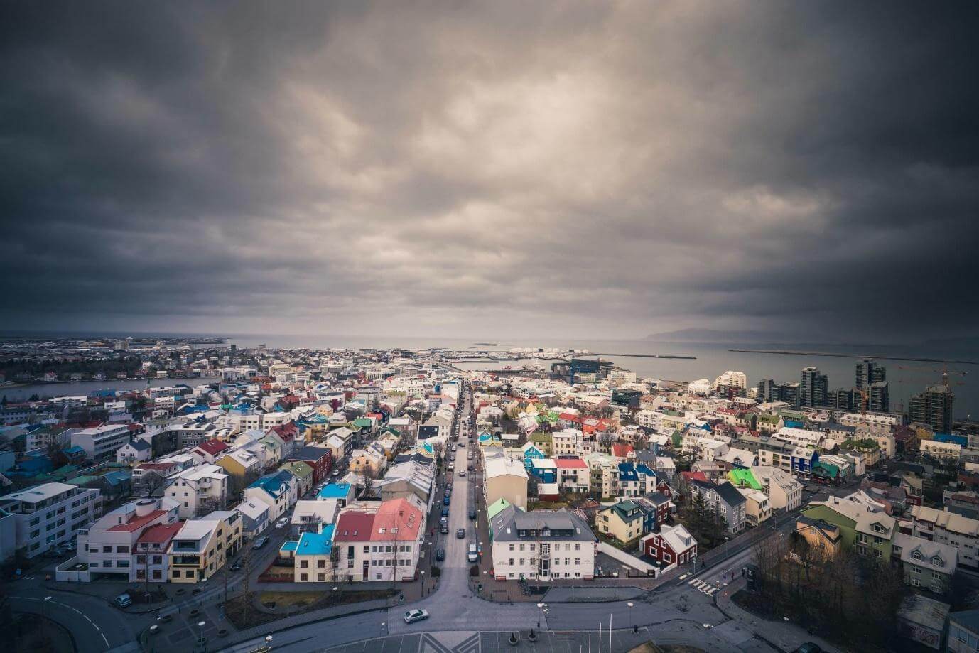 Reykjavik from above, coloured rooftops running down to the sea under grey cloud