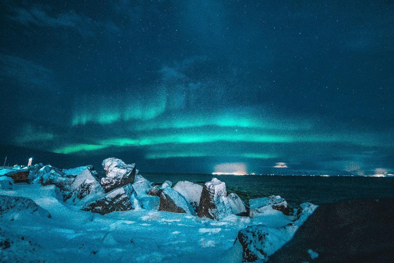 Green northern lights over an ice-strewn shoreline in Iceland