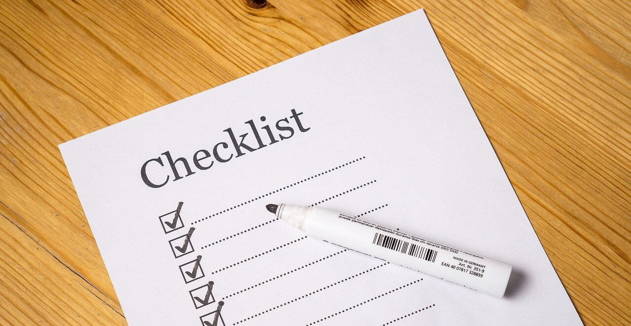 A printed checklist with ticked boxes and a marker pen on a wooden table
