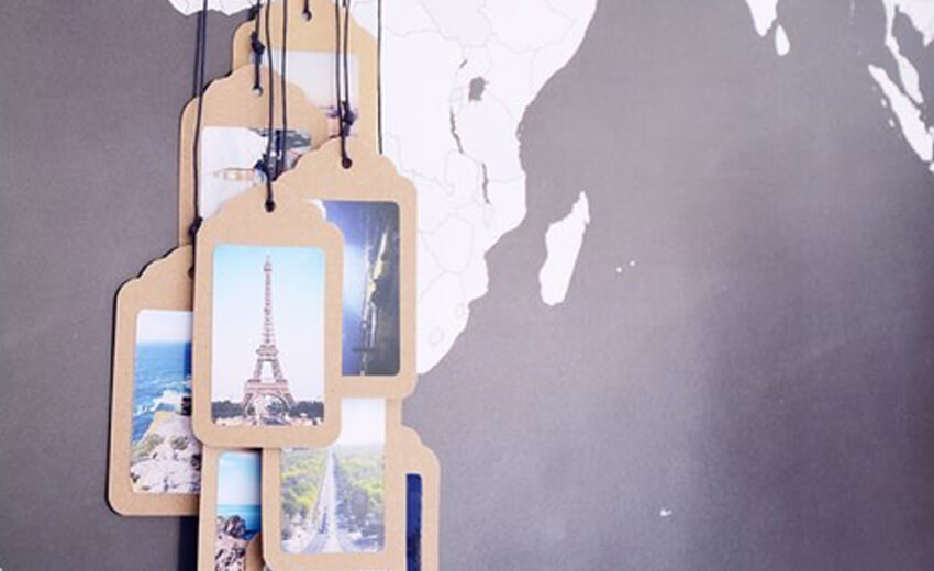 Printed travel photographs clipped to a hanging garland against a wall